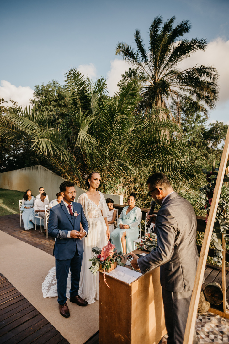 Multiethnic couple on wedding ceremony with unrecognizable officiant and guests